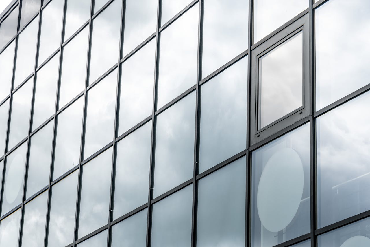 A modern glass facade reflecting a cloudy sky, showcasing contemporary architecture.